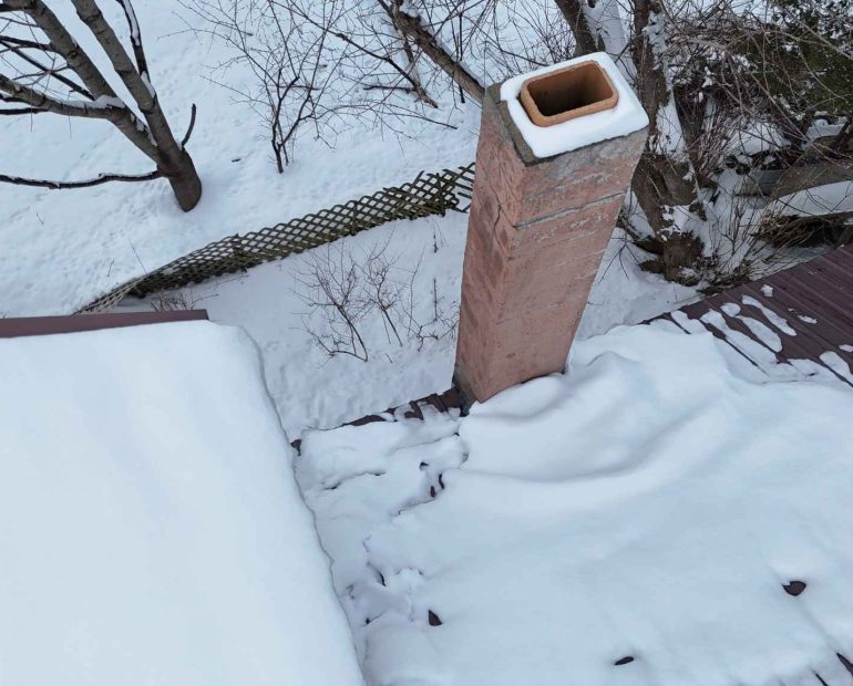 Snow and ice buildup around chimney causing roof and flashing damage during winter