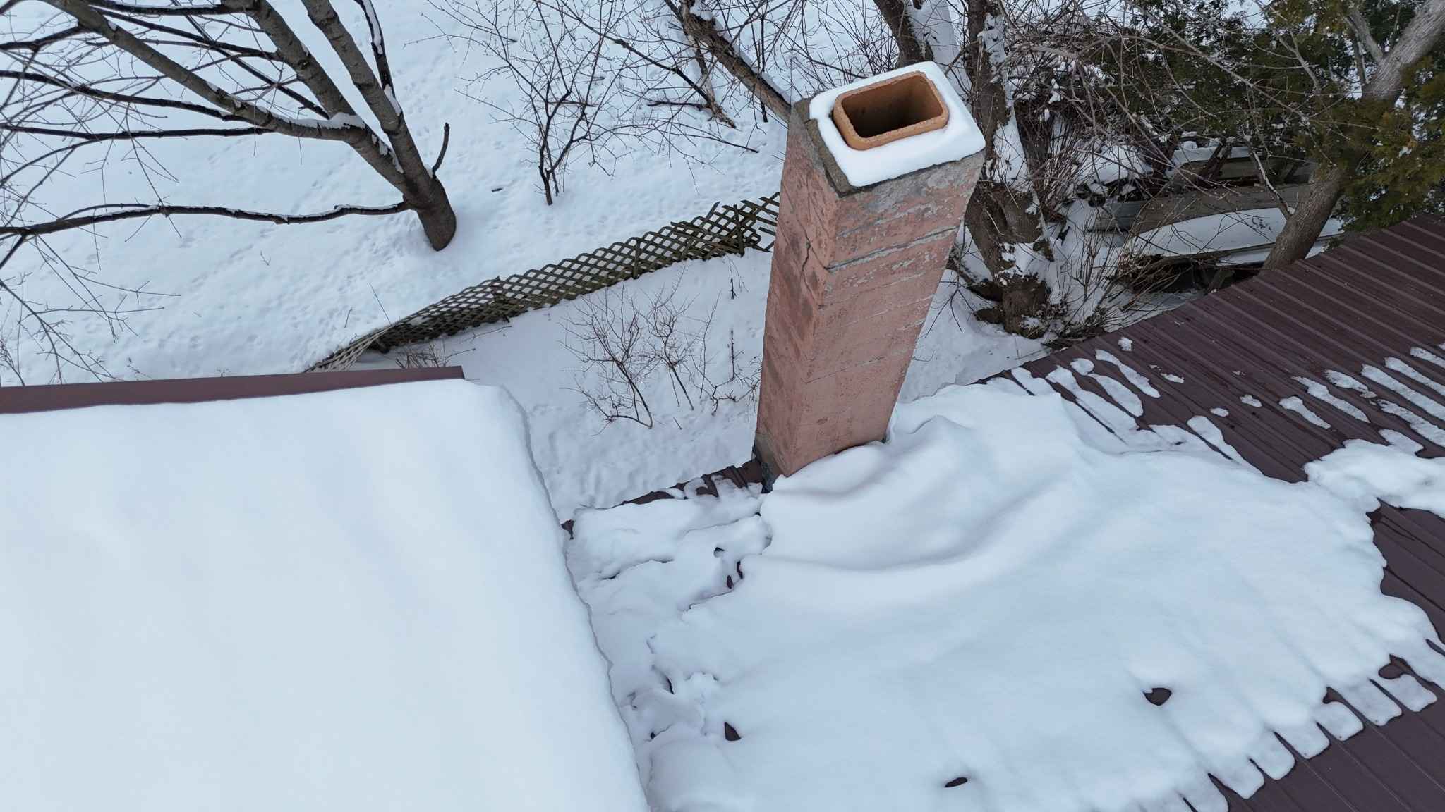 Snow and ice buildup around chimney causing roof and flashing damage during winter