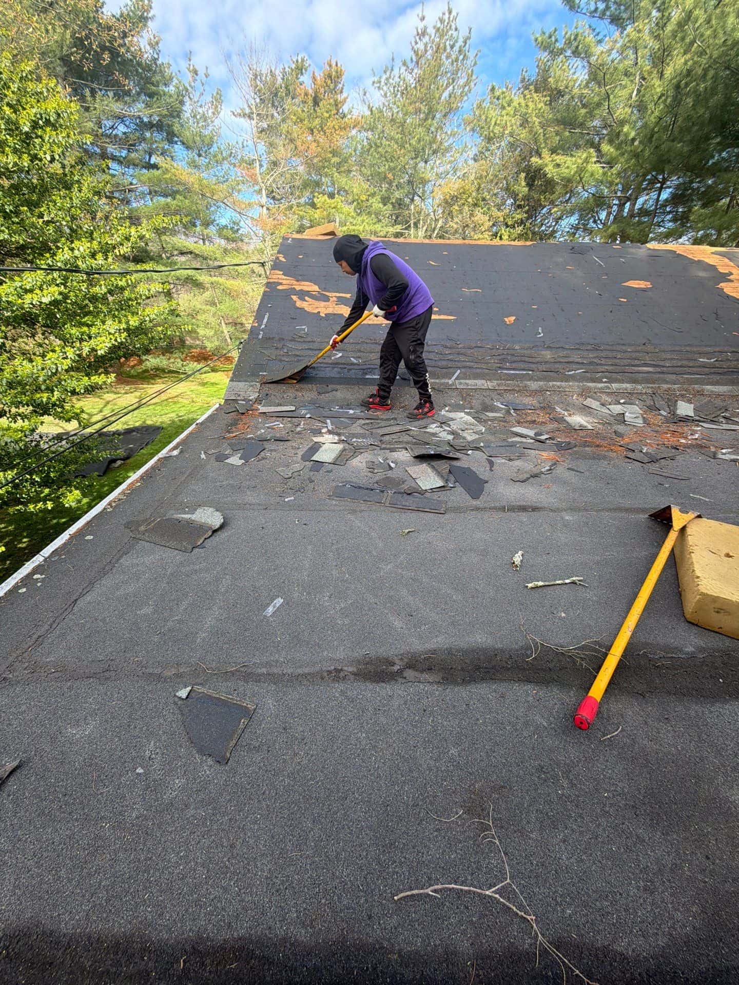 What to Expect During a Roof Replacement Project roof replacement project old shingle removal Worker removing old shingles during a residential roof replacement project to prepare for new roofing installation