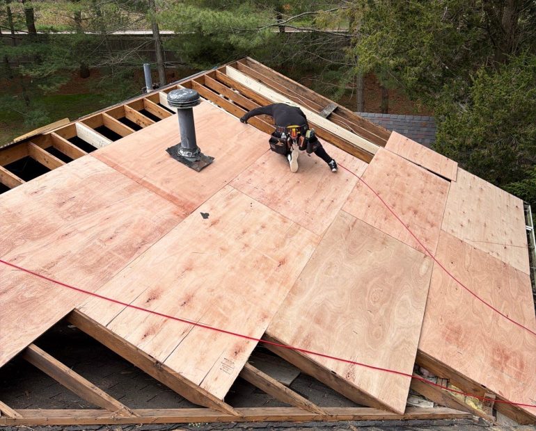 Contractor performing roof decking replacement with new plywood sheathing during a residential roof installation project.