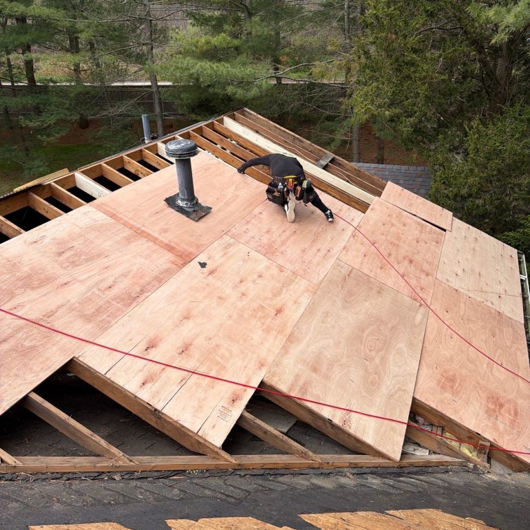 Contractor performing roof decking replacement with new plywood sheathing during a residential roof installation project.