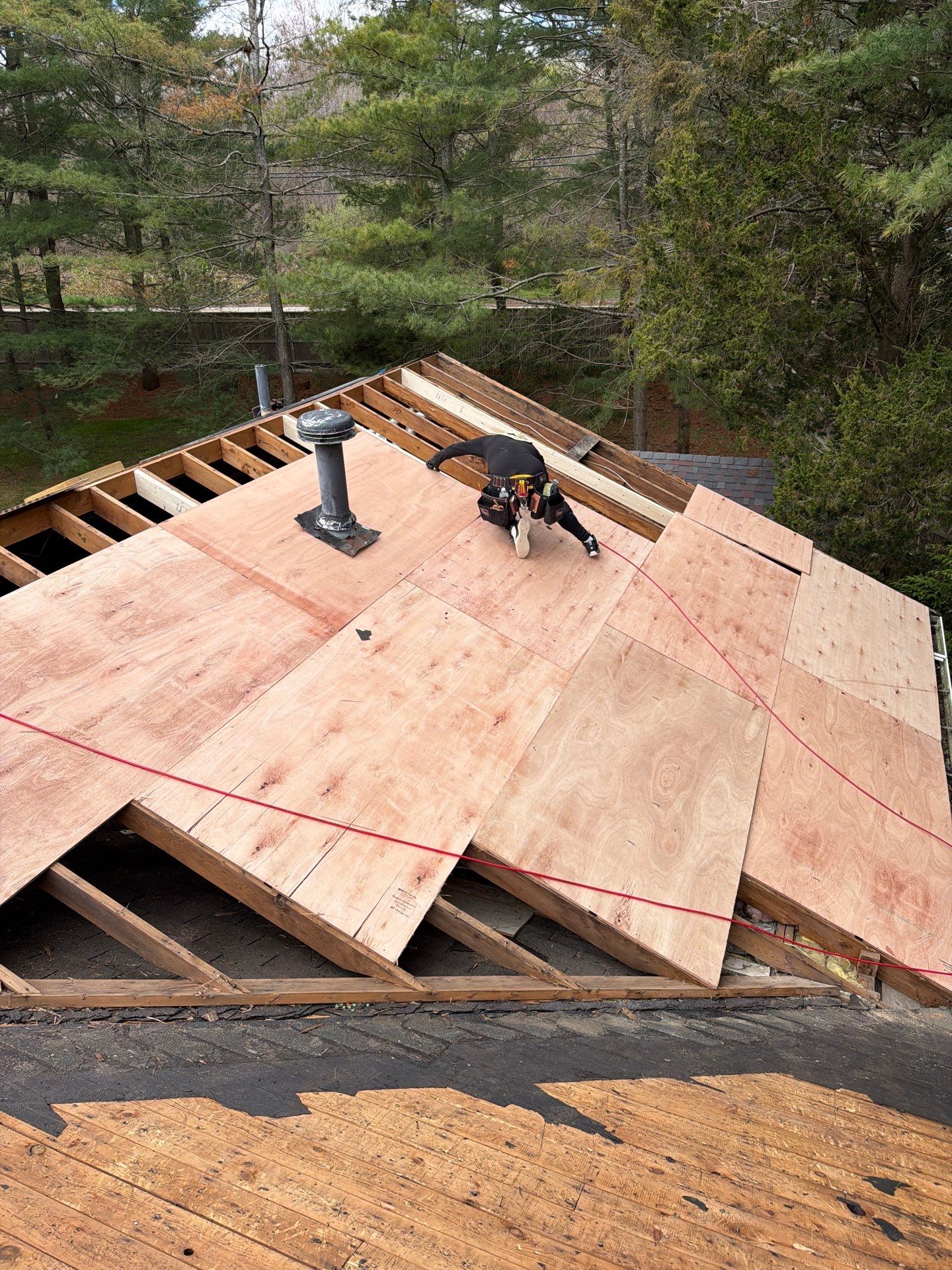 Contractor performing roof decking replacement with new plywood sheathing during a residential roof installation project.