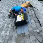 A professional worker installing a roof ventilation system on a residential shingle roof, ensuring proper airflow and attic ventilation.