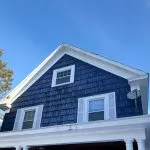 Residential home roof in winter showing snow buildup and shingle roofing system for seasonal maintenance