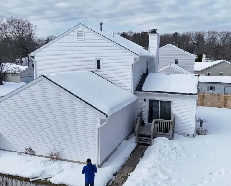 Metal Roofing Benefits: Why Many Homeowners Choose It in 2026 metal roofing benefits homeowners 2026 Snow covered residential home with sloped roof showcasing why homeowners choose durable metal roofing in 2026