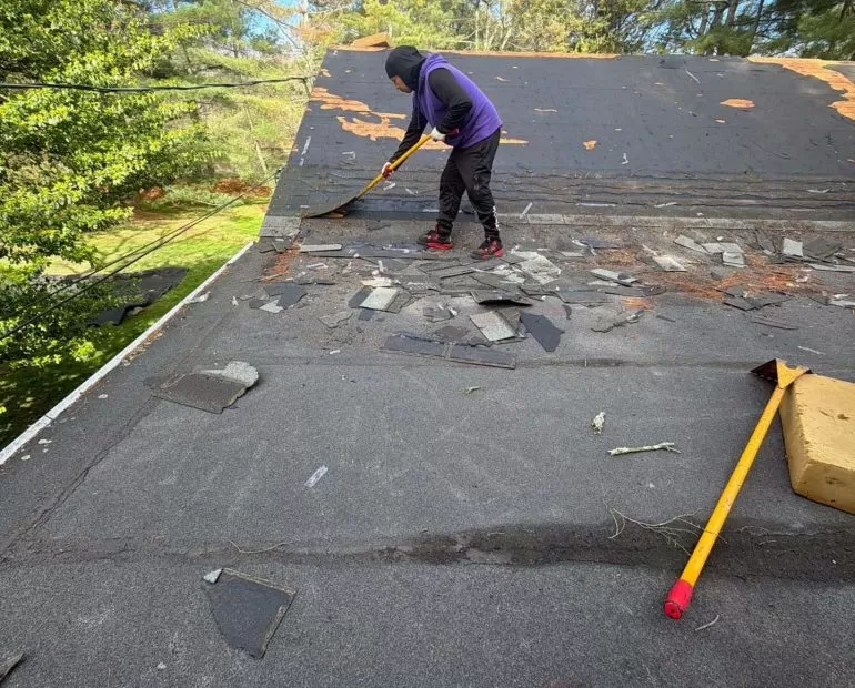 What to Expect During a Roof Replacement Project roof replacement project old shingle removal Worker removing old shingles during a residential roof replacement project to prepare for new roofing installation