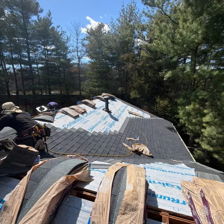 Asphalt Shingle Roof Replacement Process for Heavily Wooded Properties asphalt shingle roof replacement wooded property Asphalt shingle roof replacement in progress on a residential home surrounded by tall trees and wooded landscaping.
