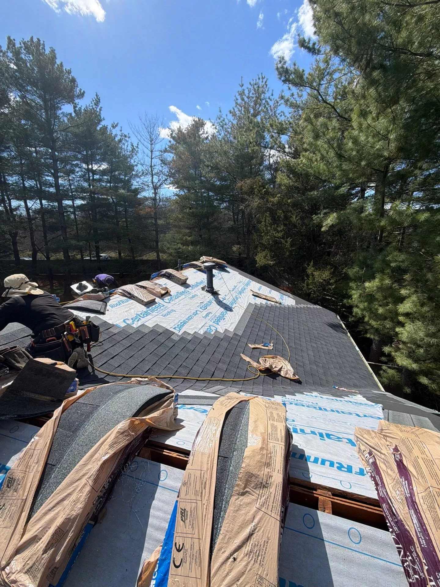 Asphalt Shingle Roof Replacement Process for Heavily Wooded Properties asphalt shingle roof replacement wooded property Asphalt shingle roof replacement in progress on a residential home surrounded by tall trees and wooded landscaping.