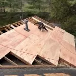 Contractor performing roof decking replacement with new plywood sheathing during a residential roof installation project.