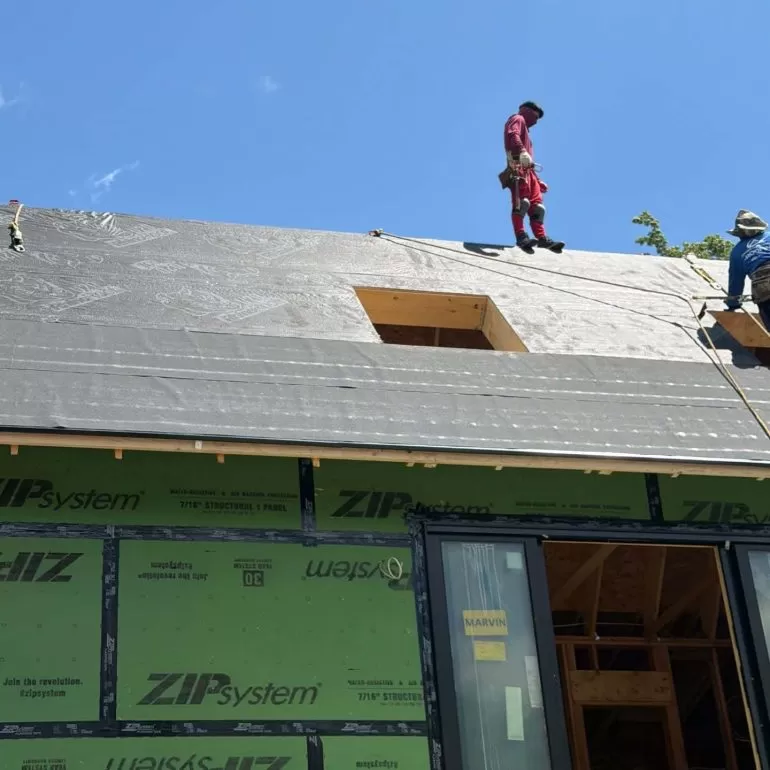 Synthetic Roofing Underlayment vs Felt: Which Is Better for Your Roof? synthetic roofing underlayment vs felt Professional roofers installing synthetic roofing underlayment over ZIP System roof sheathing before asphalt shingles on a new residential home.