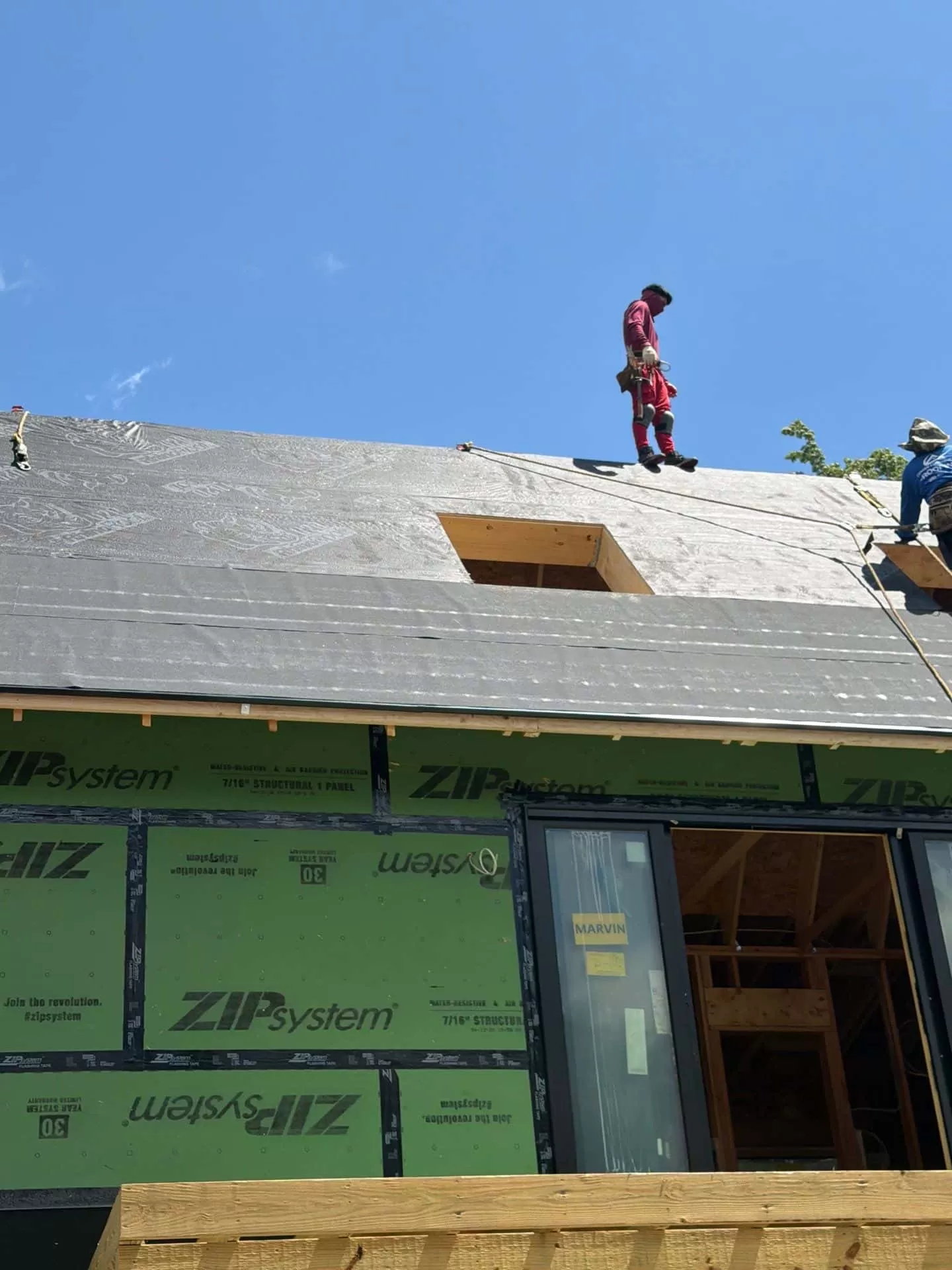 Synthetic Roofing Underlayment vs Felt: Which Is Better for Your Roof? synthetic roofing underlayment vs felt Professional roofers installing synthetic roofing underlayment over ZIP System roof sheathing before asphalt shingles on a new residential home.